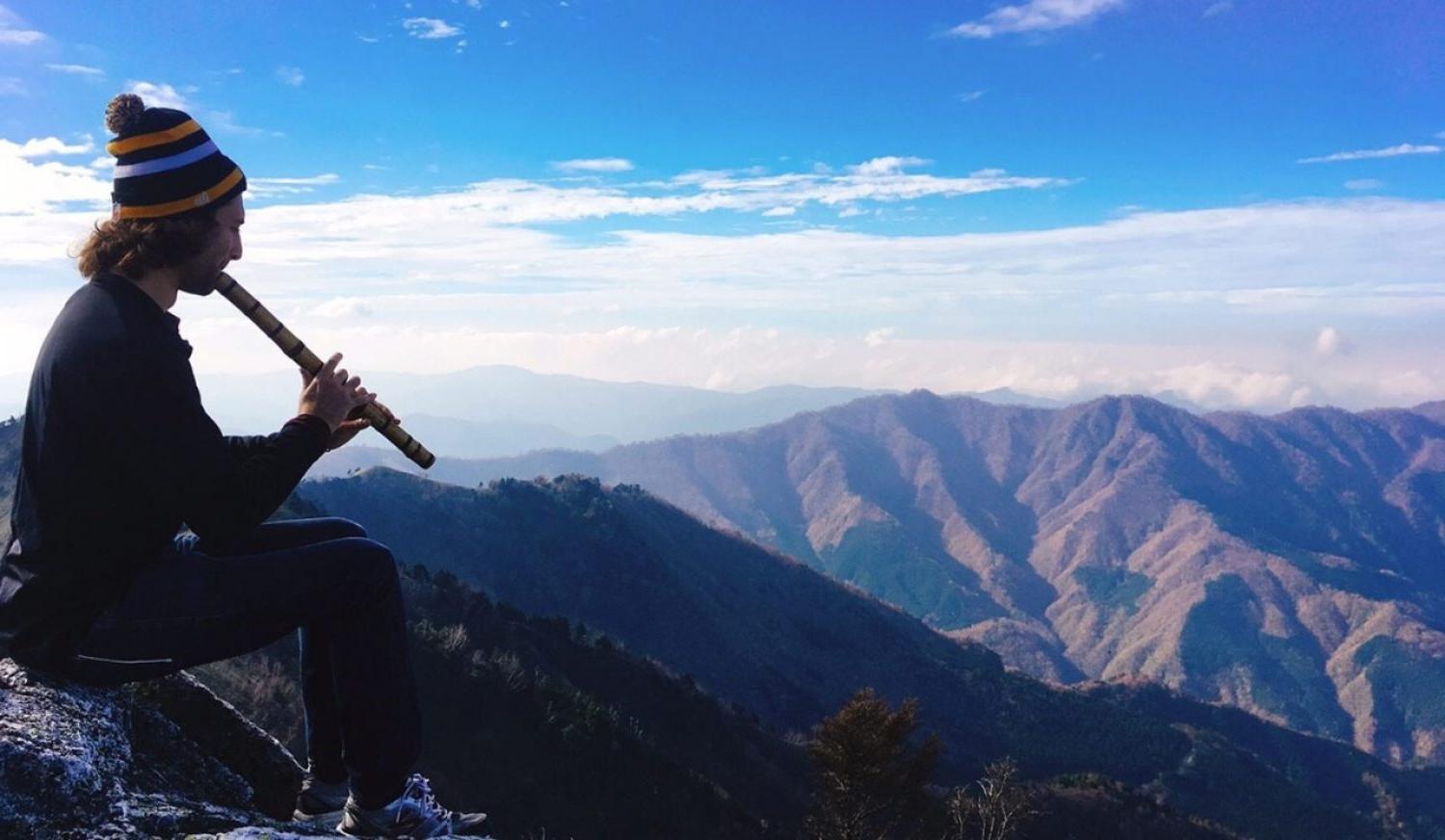 A person playing an instrument on top of a mountain
